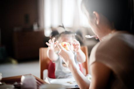 A young mother feeding her toddler daughter with baby food