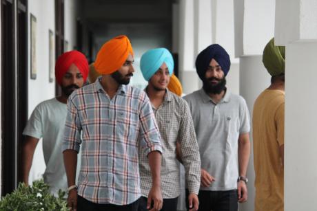 Sikh men clad in turbans walking through the verandah of a grand building